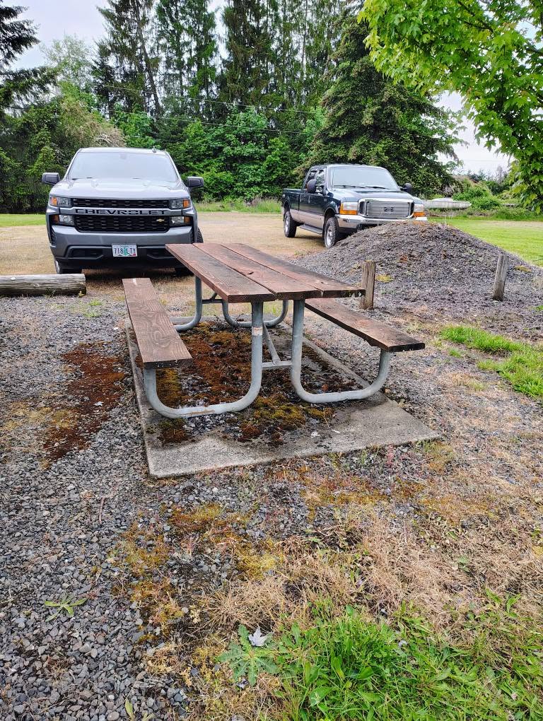 Picnic table and gravel parking with trucks